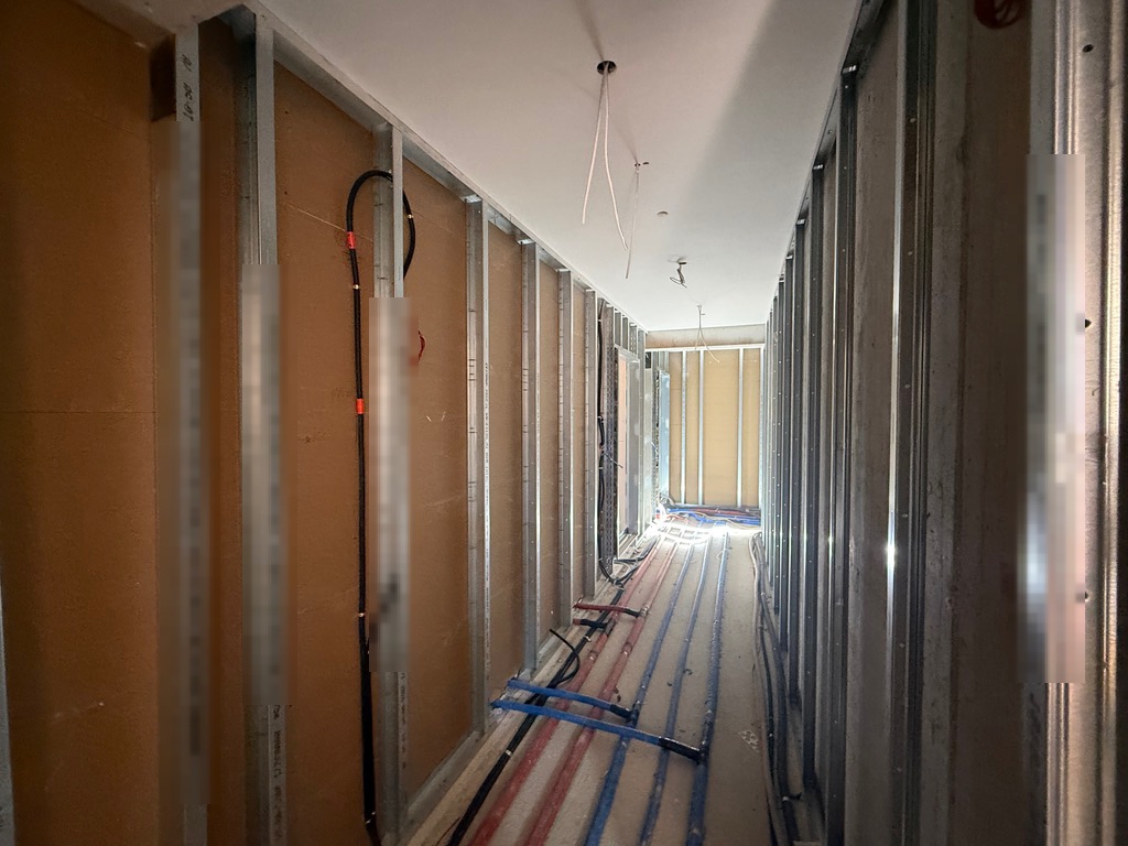 Flur mit einseitig beplankten Ständerwänden und offen verlegten Leitungen