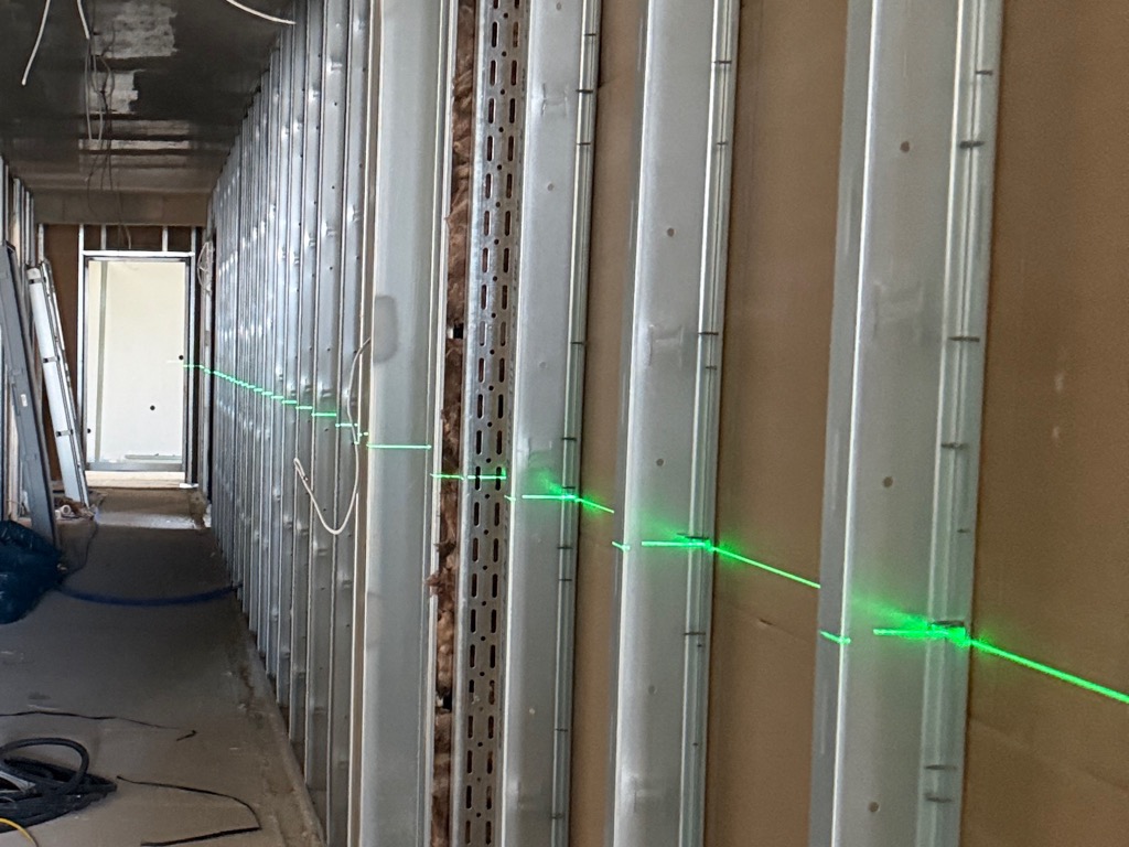 Ständerprofile in einem Flur, über die eine grüne Laserlinie läuft